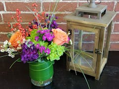 A lovely purple, orange and green arrangement, offset by an antique lantern